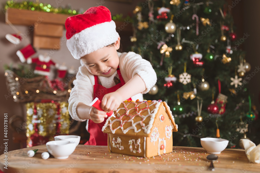 Wall mural young girl making gingerbread house at home