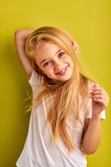girl having fun alone, touching hair. portrait of positive child girl with long blond hair isolated...