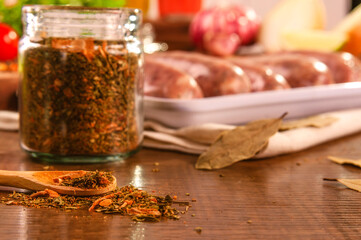 Chimichurri on wooden table with unfocused brazilian sausages in the background