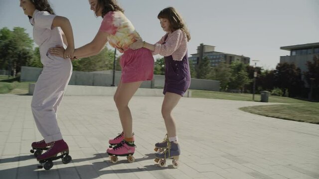 Slow motion tracking shot of girls roller skating in a row / Salt Lake City, Utah, United States