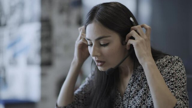 Close up of stressed businesswoman removing headset in call center / Pleasant Grove, Utah, United States