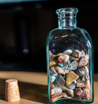 Glass Bottle Half Full Of Rounded Pebbles And Rocks