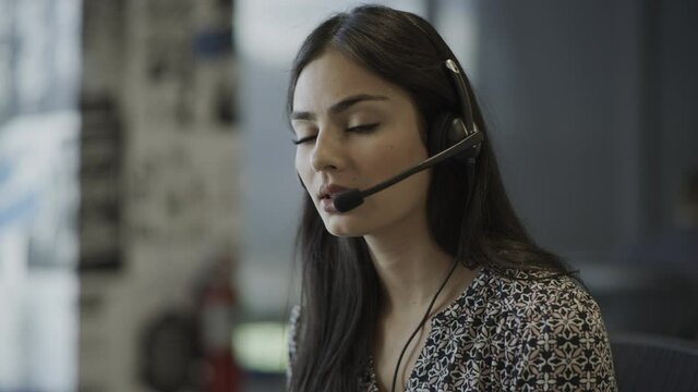 Close up of serious businesswoman wearing headset talking in call center / Pleasant Grove, Utah, United States