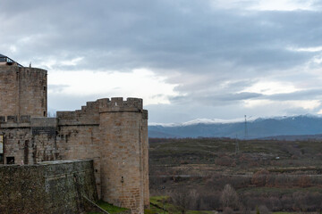 Fototapeta na wymiar Horizontal panoramic view of a stone castle tower in Puebla de Sanabria and snow-capped mountains in the background
