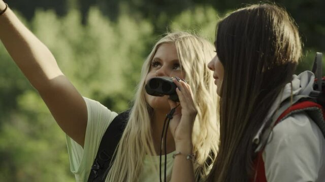 Close up of girls sharing binoculars in forest / Tibble Fork, Utah, United States