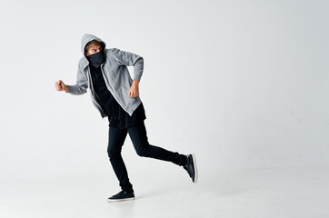 male hacker in a gray sweater stealing black mask on his face