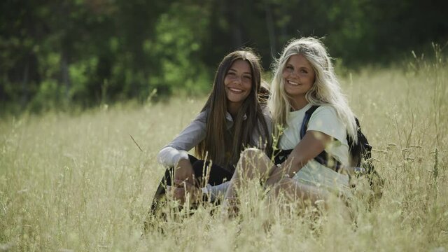 Portrait of smiling teenage girls sitting on hill / Tibble Fork, Utah, United States
