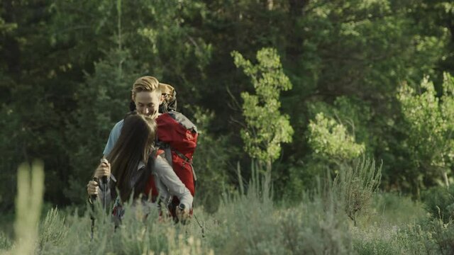 Teenage couple hiking with walking sticks in forest / Tibble Fork, Utah, United States