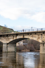 Fototapeta premium Stone bridge with people walking in a sunset.