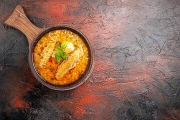 top view chicken soup in wooden bowl with handle on dark red background with free space
