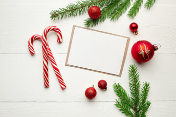 Fototapeta na wymiar Greeting card mockup with candy canes, red christmas decorations and fir tree branches on white