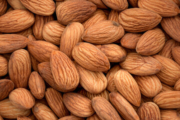 Nuts backgrounds, almonds abundance and healthy snack concept nourishment with full frame on a heap of natural brown almond kernels in background