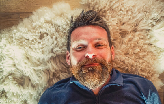 portrait of happy relaxed man laying on sheepskin rug
