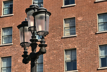 Fototapeta na wymiar Antique luminous triple street lantern against the house with brick wall, Dublin, Ireland