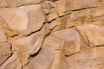Warm brow rock wall with cracks and rough texture