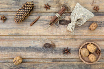 Stars anise, walnuts, small bag, cinnamon and a fir cone on the background of old wooden boards.