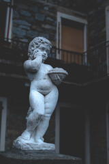 Putto statue in stone at the entrance of a villa