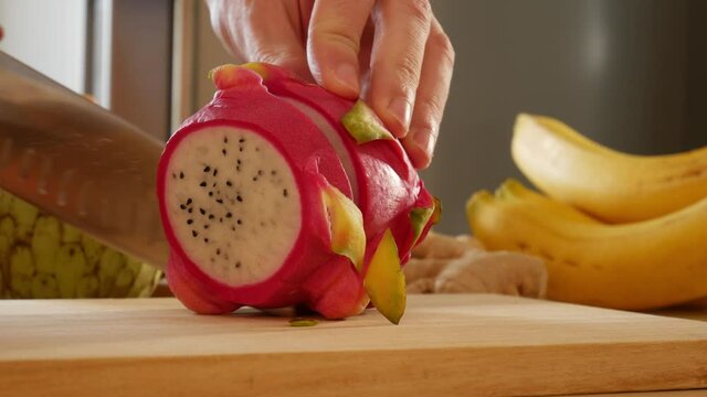 knife cuts dragon fruit on wooden cutting board, Selenicereus undatus cutted, cutting pitahaya, cactus fruit video