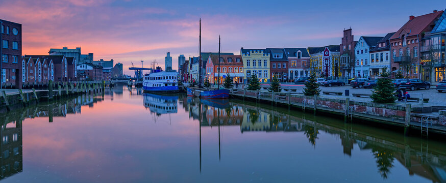North Sea port city of Husum at Christmas time by sunset. "The gray town by the sea." View on Christmas port of Husum with Christmas trees and beautiful sunset.