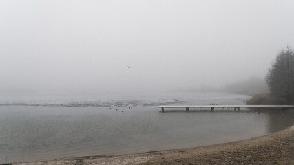 Molo nad zamarzniętym jeziorem we mgle
