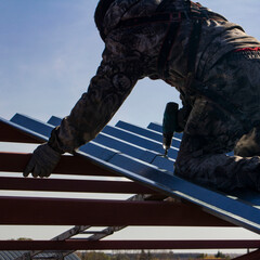 an industrial climber worker, insured on a safety rope, performing a task of installing metal structures at a high altitude