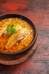 bottom view chicken soup in wooden bowl on chopping board on dark red background