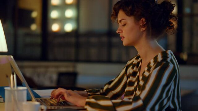 Beautiful woman typing on computer in coworking. Girl working on laptop indoors.