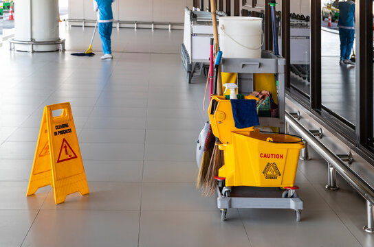 The warning signs cleaning in process the floor of the building and janitorial car parked in back to remind people to walk safely.