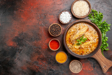 top view chicken soup in wooden bowl on chopping board a bowl of rice different spices parsley on dark red background with free space