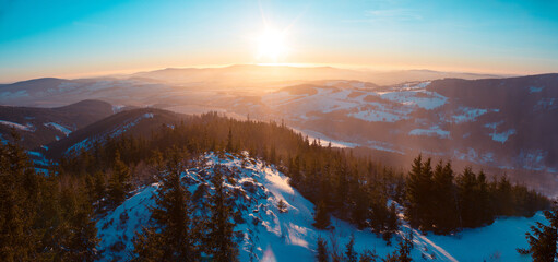 Fototapeta na wymiar Panoramatic view on Eagle and Jesenik mountains from Kralicky Sneznik summit in winter at sunset. Snow is lying on hills with a lot of trees.