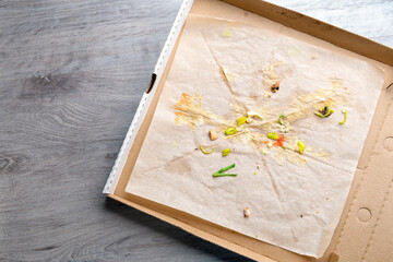 Used opened pizza box with stains and crumbs inside on table background