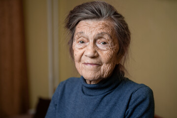 Older cute woman of ninety years old Caucasian with gray hair and wrinkled face looks at camera,...
