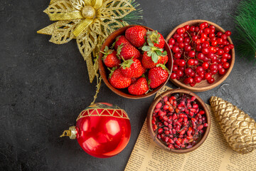 top view fresh red cranberries with other fruits around christmas toys on dark background fruit color xmas holiday berry