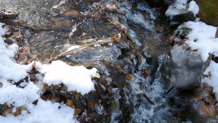 Partially frozen and snow covered creek in beautiful prír with icicles