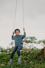 African American boy swinging on a swing in nature