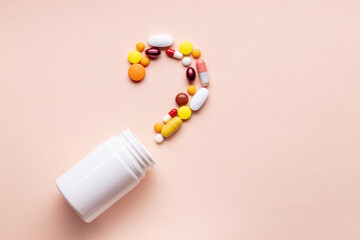 assorted pills and capsules near blank bottle isolated pink background. above view. pharmacy concept
