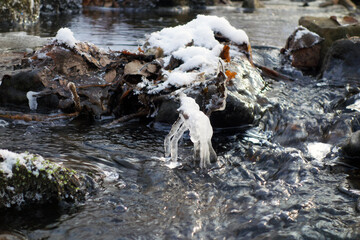 Partially frozen and snow covered creek in beautiful prír with icicles