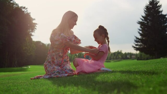 Cheerful mother and daughter fooling outdoor. Family playing in city park.