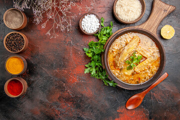 top view chicken soup on chopping board parsley a bowl of rice sea salt different spices lemon slice on dark red background with copy space