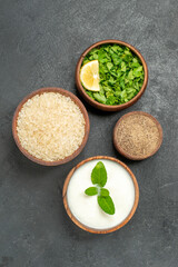 top view bowls with rice natural yogurt parsley pepper on dark background