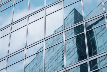 Fototapeta na wymiar glass wall reflecting modern glazed office building and sky for business background