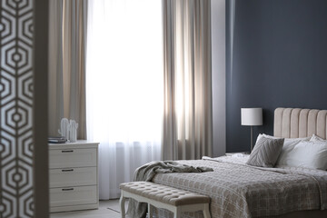 Beautiful curtains on window in stylish bedroom interior