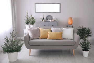 Fototapeta na wymiar Beautiful room interior with decorated Christmas firs and comfortable sofa
