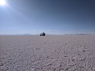 wide expanse of salt flat with small van in bolivia