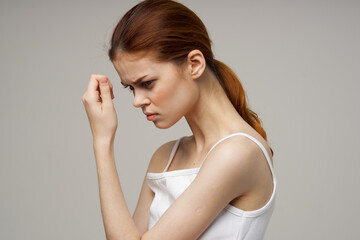 red-haired woman touching face with hands on gray background cropped view