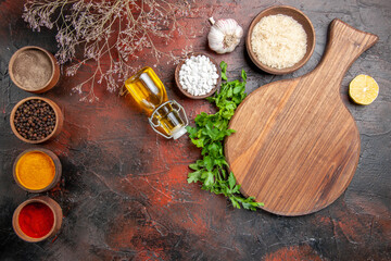 Fototapeta na wymiar top view chopping board parsley a bowl of rice sea salt different spices lemon slice oil garlic on dark red background with copy space