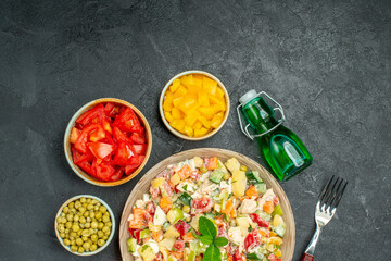top close view of bowl of veggie salad with vegetables oil bottle and fork on side with free place for text on dark background