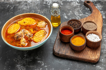 Side view of spices diversity and chicken soup on dark background