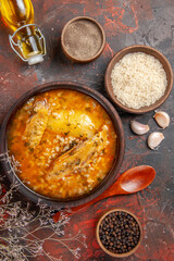 top view chicken soup bowls with pepper rice garlic spoon oil on dark red background