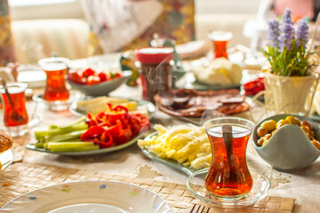 Happy family have breakfast together. Delicious rich Traditional Turkish breakfast include tomatoes, cheese, eggs, bagels, olives and tea cups. Ramadan Suhoor aka Sahur (morning meal before fasting). 